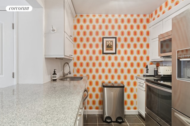 450 W 20th St Garden, Unit Garden, New York City, NY 10011 - kitchen with appliances with stainless steel finishes, wallpapered walls, a sink, white cabinetry, and baseboards