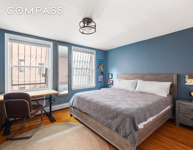 bedroom featuring wood finished floors, baseboards, and baseboard heating