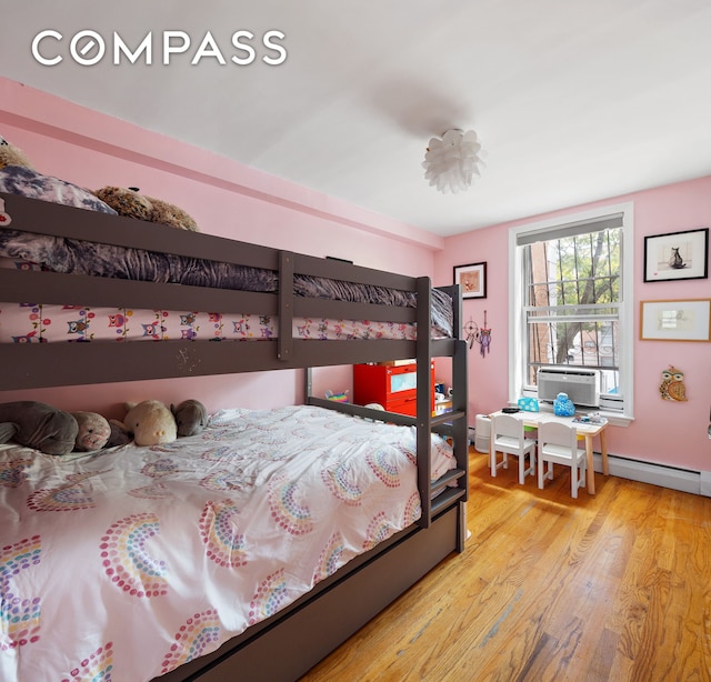 bedroom with wood finished floors, a baseboard heating unit, and cooling unit