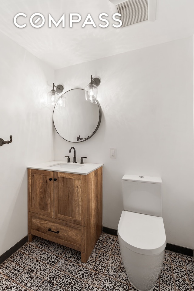 bathroom with baseboards, vanity, and toilet