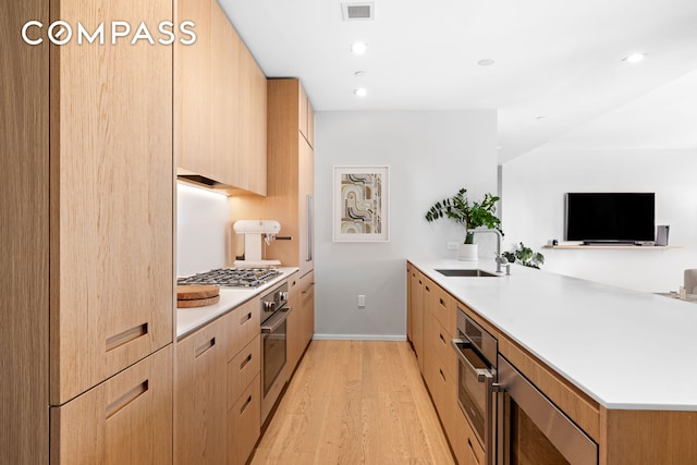 98 Front St Ph, Ph, New York City, NY 11201 - kitchen with visible vents, a peninsula, light wood-style floors, a sink, and stainless steel appliances