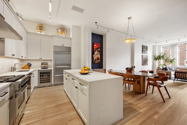 252 7th Ave Unit 6W, New York City, NY 10001 - kitchen with rail lighting, high quality appliances, under cabinet range hood, and a breakfast bar area