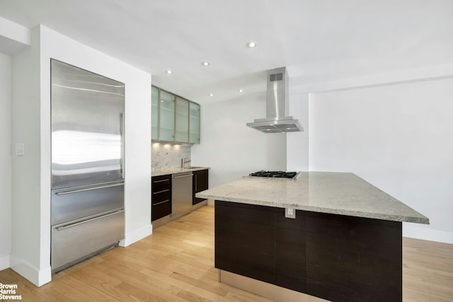 kitchen featuring stainless steel appliances, ventilation hood, light wood finished floors, tasteful backsplash, and recessed lighting