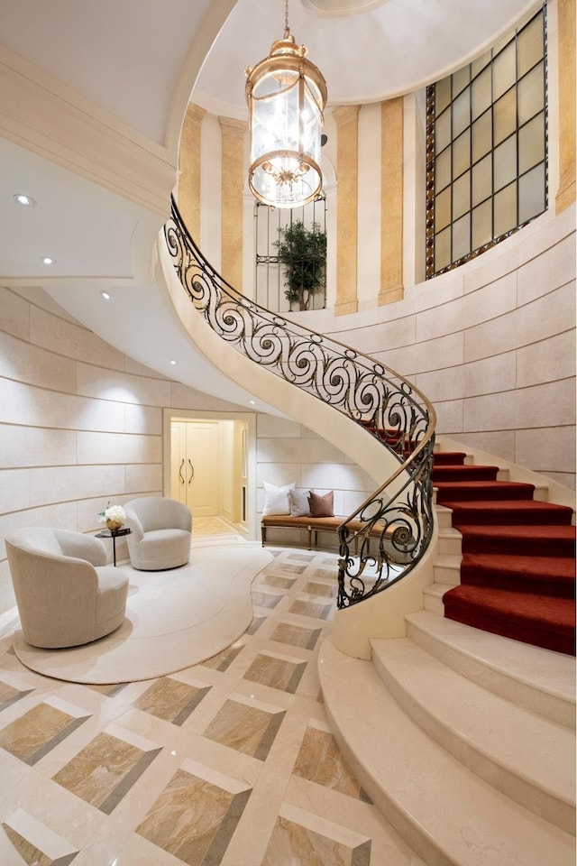 349 W 86th St, New York City, NY 10024 - stairs with a chandelier, a high ceiling, tile walls, recessed lighting, and inlaid floor details