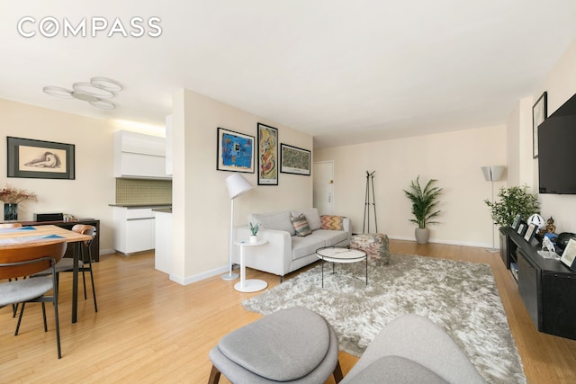 living area with light wood-type flooring and baseboards