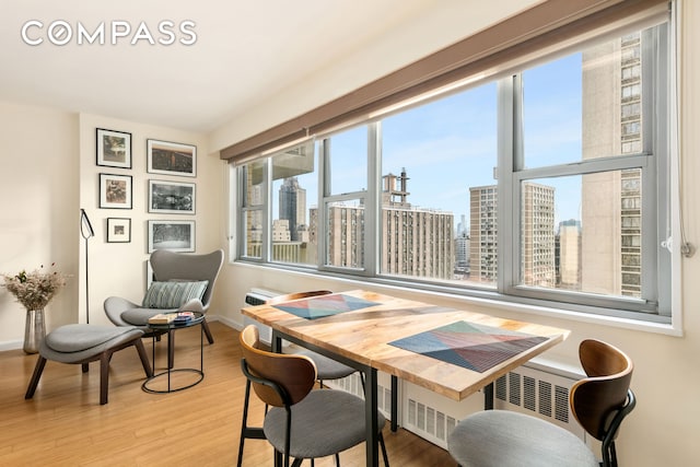 interior space with radiator, a view of city, wood finished floors, and baseboards