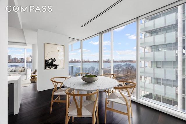 dining area featuring dark wood-style flooring, a water view, and healthy amount of natural light