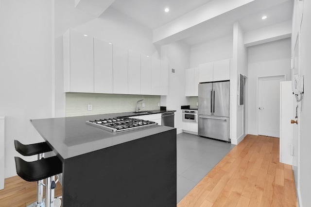 310 E 46th St Unit 15-E, New York City, NY 10017 - kitchen with appliances with stainless steel finishes, a sink, modern cabinets, white cabinetry, and a peninsula