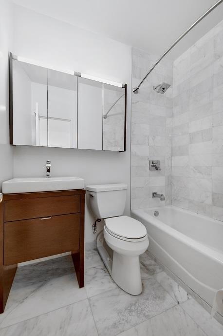 310 E 46th St Unit 15-E, New York City, NY 10017 - full bath featuring marble finish flooring, toilet, vanity, and shower / bathtub combination
