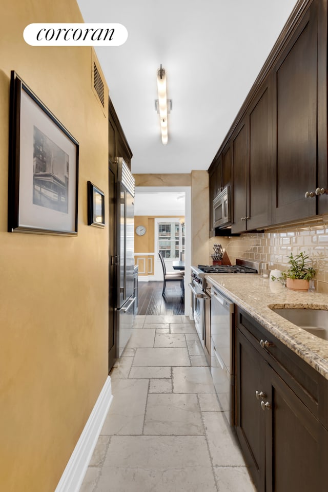 kitchen with dark brown cabinets, stone tile flooring, baseboards, appliances with stainless steel finishes, and visible vents