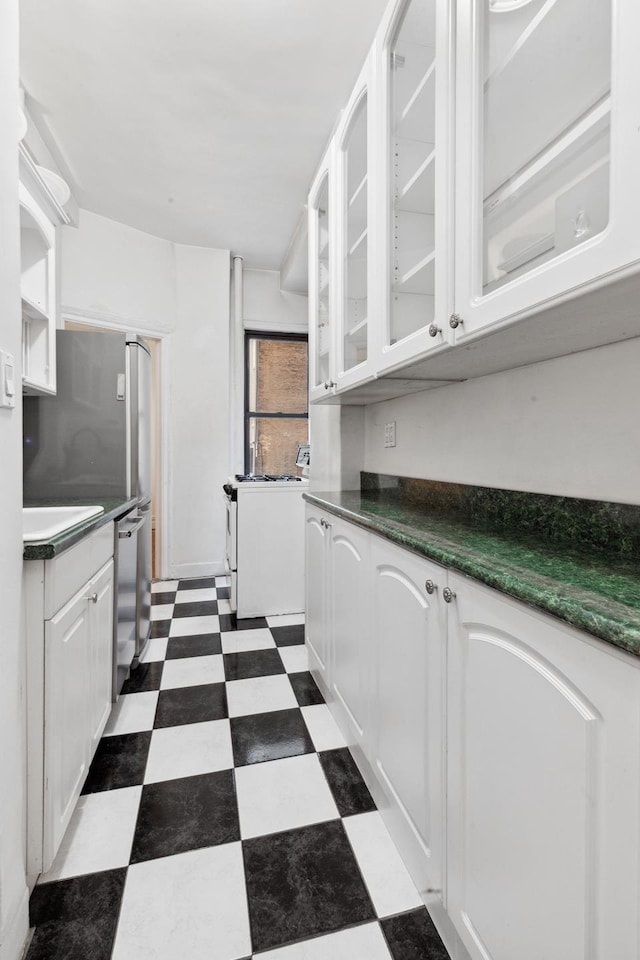 760 W End Ave Unit 1B, New York City, NY 10025 - kitchen with white range, dark flooring, stainless steel dishwasher, white cabinetry, and glass insert cabinets