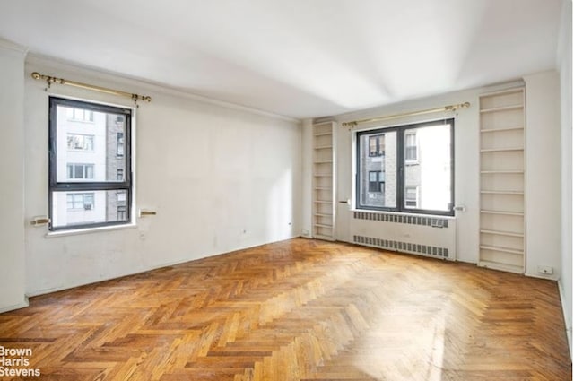 empty room with radiator, plenty of natural light, and built in features