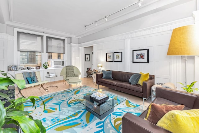 living area with track lighting, wood finished floors, a decorative wall, and cooling unit