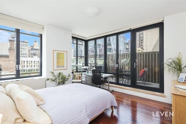 bedroom with a view of city, access to exterior, multiple windows, and hardwood / wood-style floors