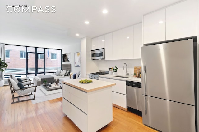 148 E 24th St Unit 4C, New York City, NY 10010 - kitchen with a center island, a sink, modern cabinets, stainless steel appliances, and white cabinetry