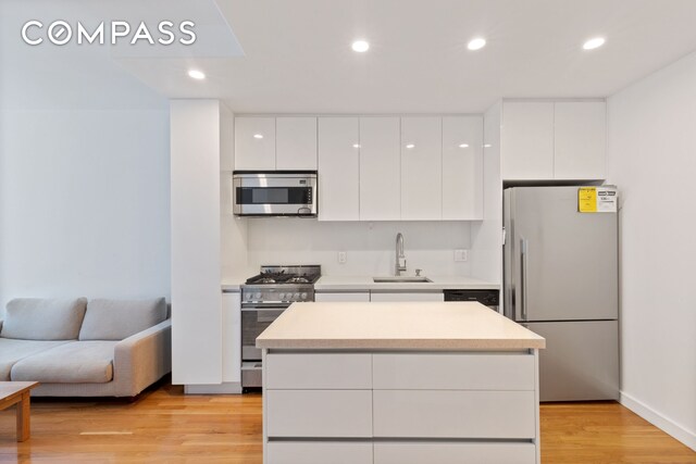 148 E 24th St Unit 4C, New York City, NY 10010 - kitchen featuring modern cabinets, white cabinets, appliances with stainless steel finishes, and a sink