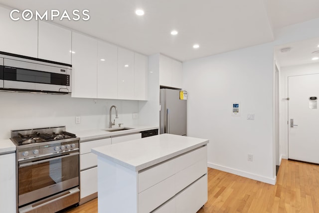 148 E 24th St Unit 4C, New York City, NY 10010 - kitchen featuring white cabinets, stainless steel appliances, light wood finished floors, a sink, and modern cabinets