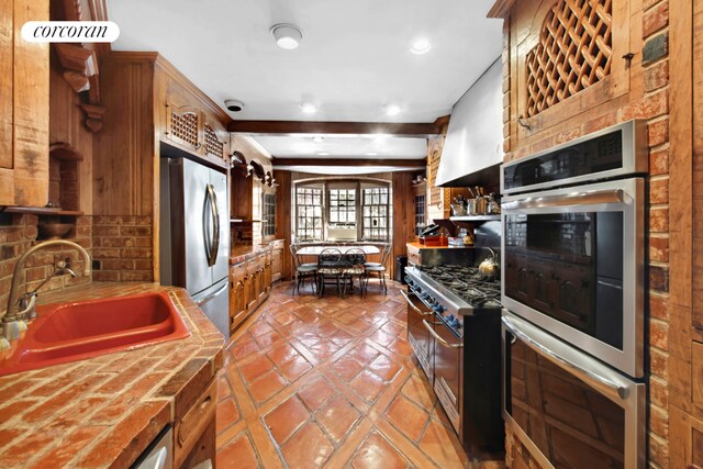 243 E 61st St, New York City, NY 10065 - kitchen with appliances with stainless steel finishes, a sink, brown cabinets, tile patterned floors, and recessed lighting