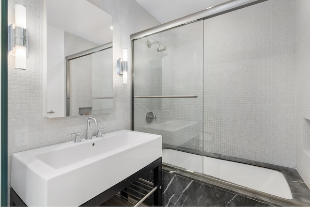 210 Lafayette St Unit 5B, New York City, NY 10012 - bathroom featuring tiled shower / bath, vanity, marble finish floors, and tile walls