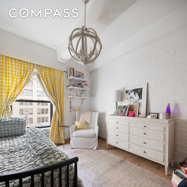 bedroom with vaulted ceiling, wood finished floors, and a notable chandelier