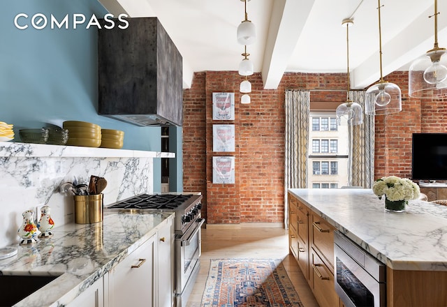 kitchen with light wood-style flooring, beam ceiling, appliances with stainless steel finishes, and brick wall