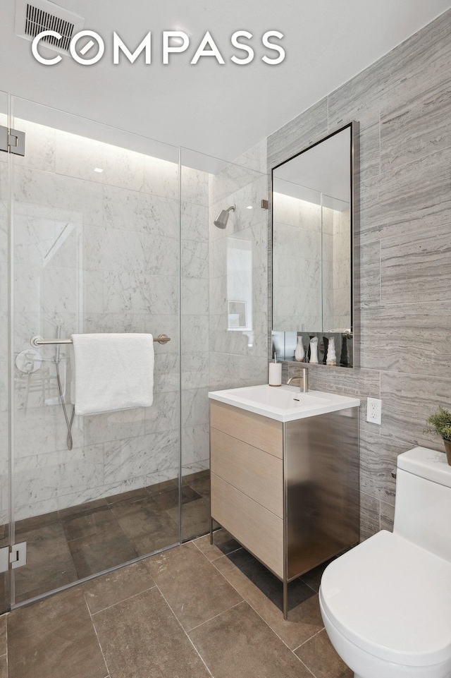 215 W 28th St Unit 11D, New York City, NY 10001 - bathroom with tile walls, tiled shower, vanity, and toilet