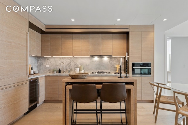 215 W 28th St Unit 11D, New York City, NY 10001 - kitchen with modern cabinets, a sink, oven, wine cooler, and light countertops