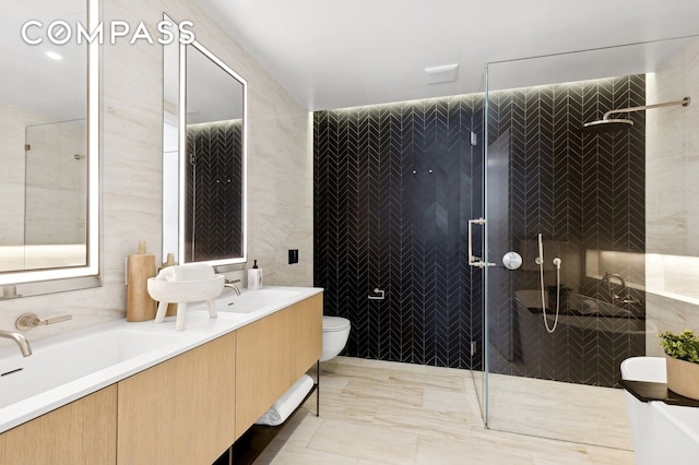 bathroom with a sink, tile walls, double vanity, a tile shower, and toilet