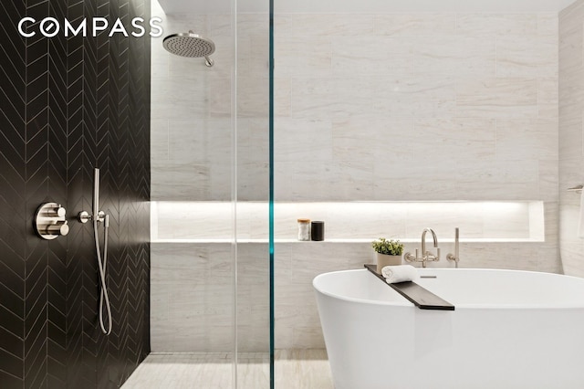 215 W 28th St Unit 11D, New York City, NY 10001 - bathroom featuring a shower stall, a freestanding bath, and tile walls