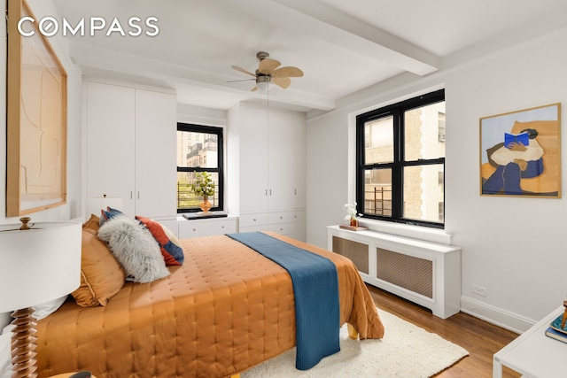 245 E 72nd St Unit 8G, New York City, NY 10021 - bedroom with radiator heating unit, beamed ceiling, wood finished floors, and a ceiling fan