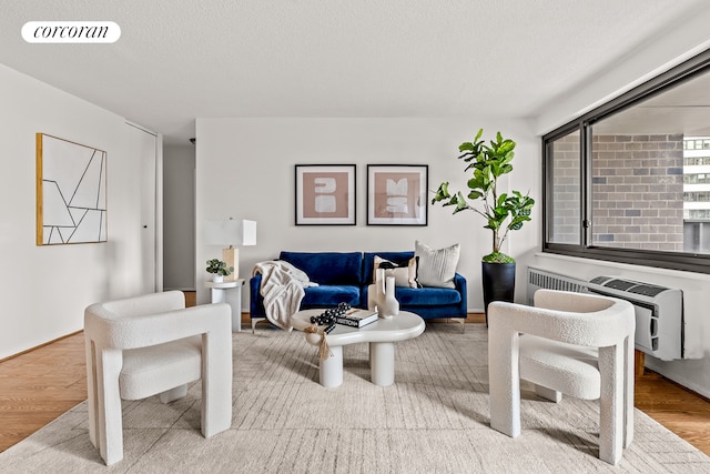 90 Gold St Unit 10L, New York City, NY 10038 - living room featuring wood finished floors, a wall mounted AC, and a textured ceiling