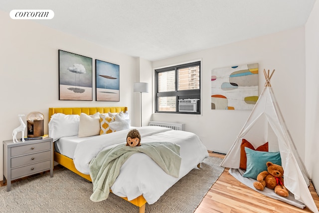 90 Gold St Unit 10L, New York City, NY 10038 - bedroom featuring radiator heating unit, wood finished floors, and cooling unit