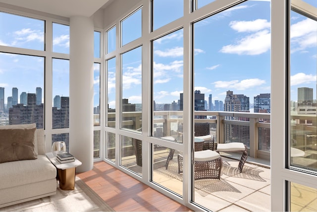 sunroom / solarium with expansive windows, a city view, and wood finished floors