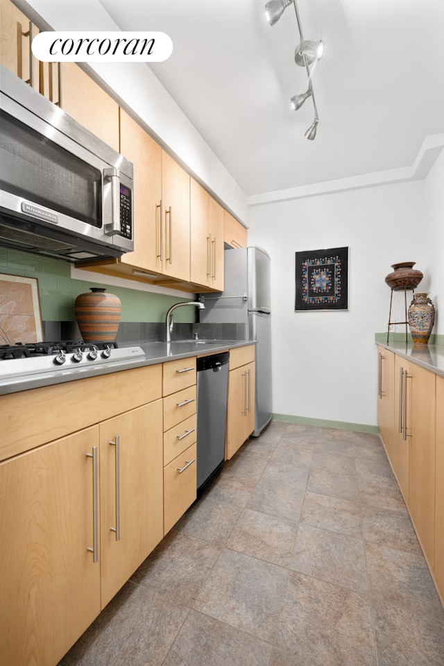 kitchen with light brown cabinetry, stainless steel appliances, baseboards, and arched walkways