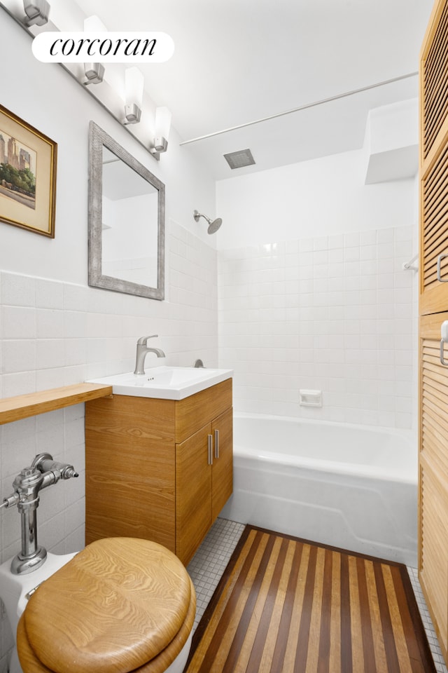 full bath featuring tile walls, tile patterned flooring, tasteful backsplash, vanity, and tub / shower combination