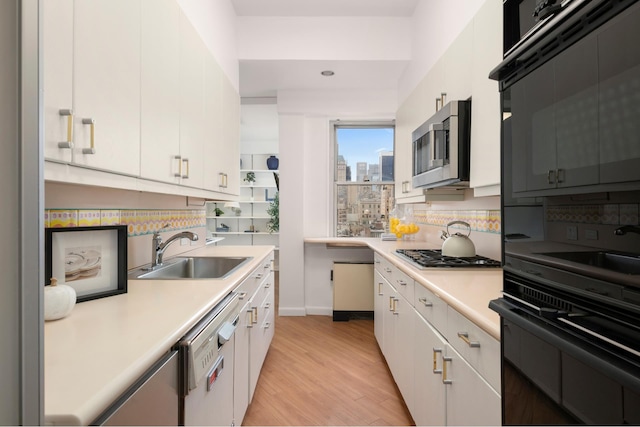 kitchen with a sink, stainless steel appliances, light countertops, decorative backsplash, and light wood finished floors
