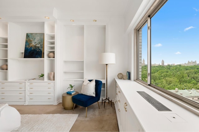 living area featuring built in features, light colored carpet, and ornamental molding