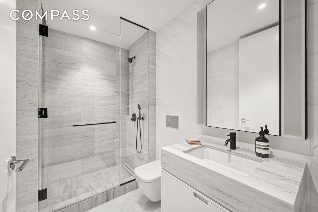 199 Chrystie St Unit 4S, New York City, NY 10002 - full bath with vanity, a shower stall, recessed lighting, marble finish floors, and tile walls