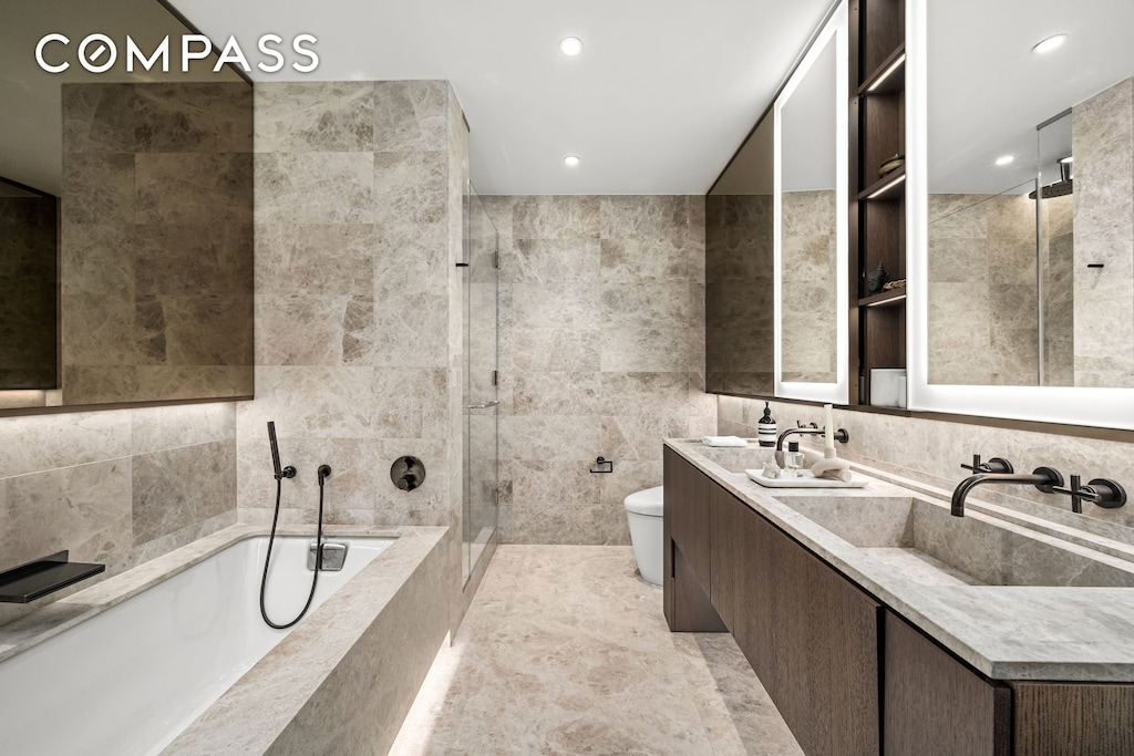 199 Chrystie St Unit 4S, New York City, NY 10002 - bathroom with a bath, tiled shower, double vanity, tile walls, and recessed lighting