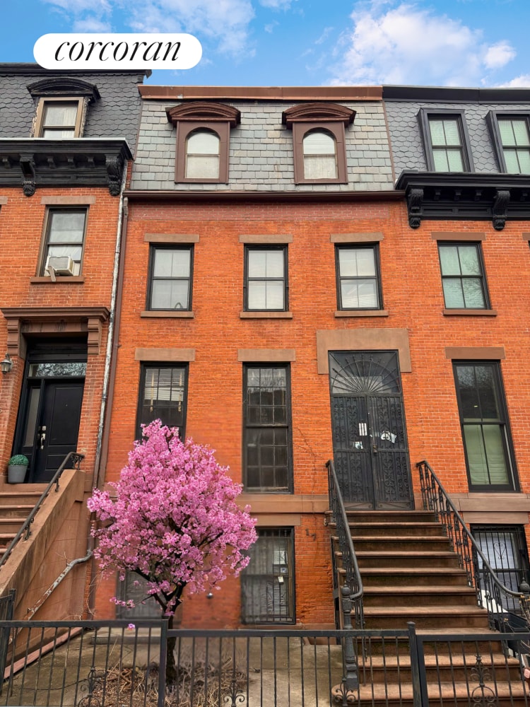 view of front of home featuring brick siding, mansard roof, and a fenced front yard