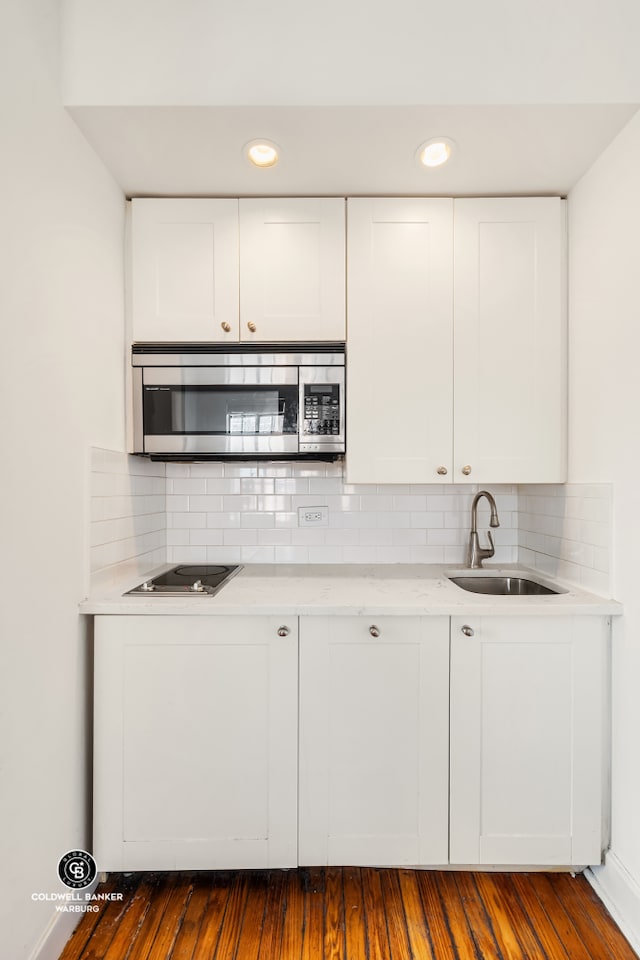 25 Tudor City Pl Unit 301, New York City, NY 10017 - kitchen with a sink, black electric cooktop, stainless steel microwave, and tasteful backsplash