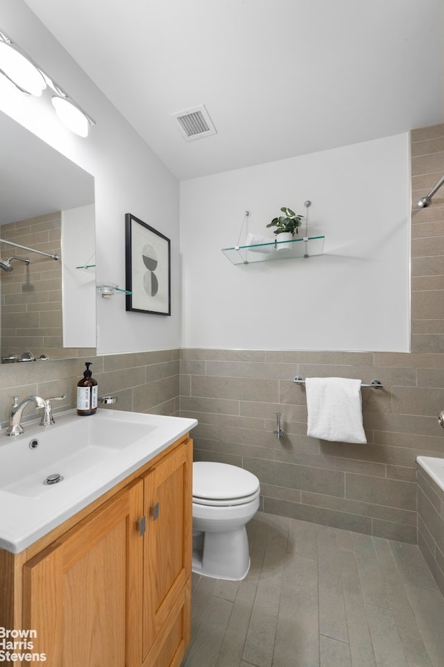 50 W 15th St Unit C1, New York City, NY 10011 - full bathroom with visible vents, toilet, tiled shower, and tile walls
