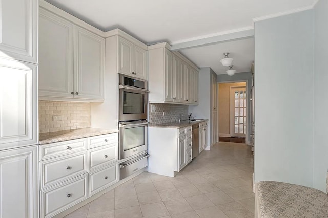 kitchen with a warming drawer, stainless steel appliances, backsplash, a sink, and light tile patterned flooring