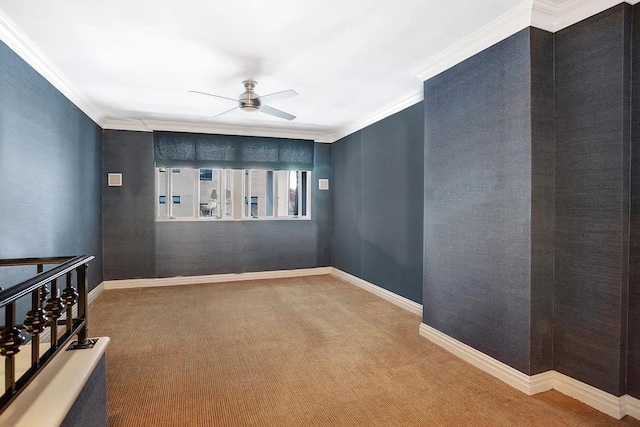 carpeted spare room with ceiling fan, ornamental molding, and baseboards