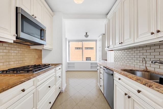 kitchen featuring stainless steel appliances, white cabinetry, a sink, and light tile patterned floors
