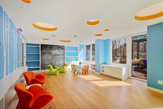 playroom featuring built in features, wood finished floors, and baseboards