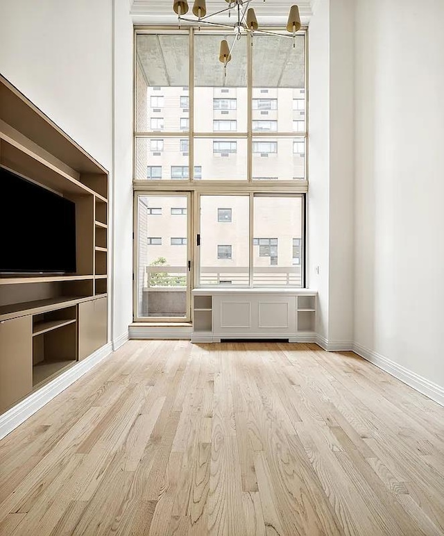 unfurnished living room with wood finished floors, baseboards, and floor to ceiling windows