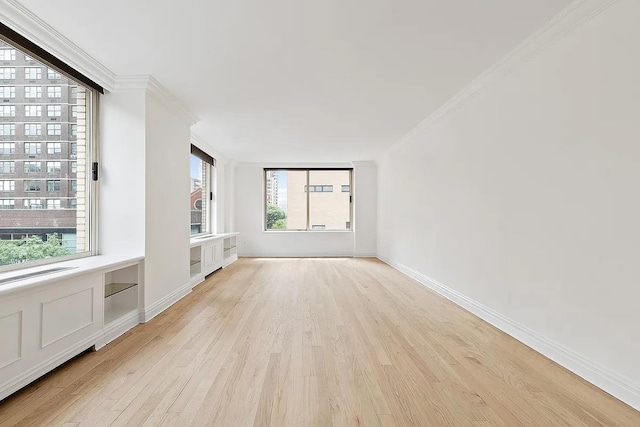 unfurnished living room featuring light wood-style flooring, crown molding, and baseboards