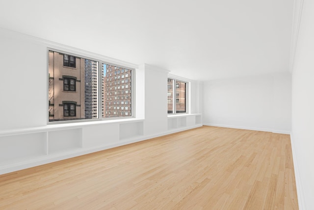 unfurnished room with wood finished floors, baseboards, and ornamental molding
