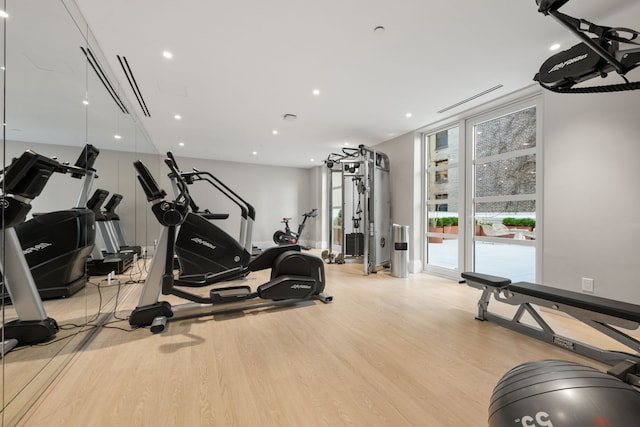 workout area with light wood finished floors and recessed lighting